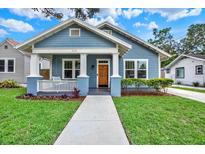 Charming blue home featuring a well-manicured lawn and inviting front porch with columns at 111 E Jean St, Tampa, FL 33604