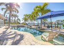 Inviting backyard pool area surrounded by lush palm trees, with waterfront access and comfortable lounge chairs at 11160 8Th E St, Treasure Island, FL 33706