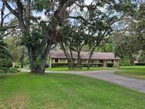 Ranch style home with circular driveway, mature trees and professional landscaping at 11307 Sandpine Rd, Riverview, FL 33569