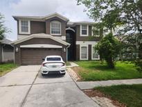 Charming two-story home featuring a two-car garage and well-maintained front lawn and a modern white car in the driveway at 1753 Open Field Loop, Brandon, FL 33510