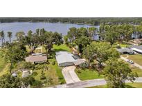 Stunning aerial view of a lakefront home, featuring a spacious yard, lush landscaping, and a sparkling pool, all with lake access at 21906 Shamu Dr, Land O Lakes, FL 34639
