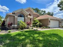 Landscaped front yard and well-maintained exterior of a single-Gathering home with arched window and attached garage at 28826 Windover St, Wesley Chapel, FL 33545