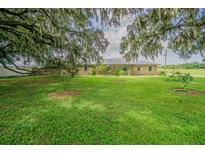 Charming brick home with lush, green front yard, mature trees, and metal roof at 3505 Medulla Rd, Plant City, FL 33566