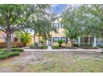 Charming two-story home featuring a cheerful yellow exterior, blue shutters, and a neatly landscaped front yard with mature trees at 511 Winterside Dr, Apollo Beach, FL 33572