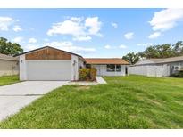 Charming single-story home with a well-maintained lawn, mature trees, and an attached two-car garage at 6370 Elmhurst Dr, Pinellas Park, FL 33782