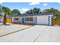 Charming single-story home with a vibrant blue door, well-maintained landscaping, and a spacious driveway at 11520 Meadow Dr, Port Richey, FL 34668