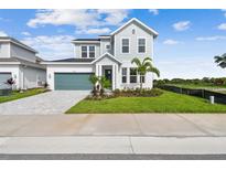 Charming two-story home featuring manicured landscaping, a paved driveway, and a teal garage door at 1583 Running Tide Pl, Sarasota, FL 34240