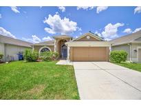 Charming single-story home featuring a well-manicured lawn, attached garage, and beautiful landscaping at 2527 Butterfly Landing Dr, Land O Lakes, FL 34638