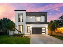 Modern two-story home with a gray garage door, stylish windows, and well-manicured lawn at twilight at 2707 Ridgewood Ave, Tampa, FL 33602