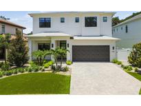 Elegant two-story home featuring a modern design, manicured lawn, and a stylish dark wood-tone garage door at 4109 W Inman Ave, Tampa, FL 33609