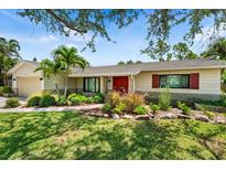 Charming single-story home boasts a well-manicured lawn, mature trees and plants, and a welcoming red front door at 4739 114Th N St, St Petersburg, FL 33708
