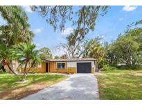 Charming single-story home featuring a gray driveway and tropical landscaping at 5614 Bay Boulevard, Port Richey, FL 34668