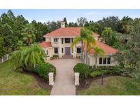 Elegant home featuring a red tile roof, manicured landscaping, and a brick driveway leading to the front entrance at 7803 Mathern Ct, Lakewood Ranch, FL 34202