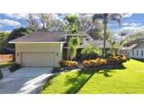 Charming two-story home features a well-manicured lawn, colorful landscaping, and an attached two-car garage at 852 Village Way, Palm Harbor, FL 34683
