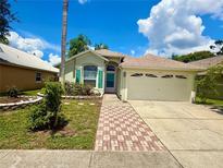 Charming single-story home with a well-manicured lawn, lush landscaping, and a brick pathway leading to the entrance at 9614 Long Meadow Dr, Tampa, FL 33615