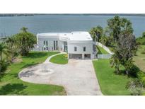 Stunning waterfront property featuring a modern, white home with lush landscaping and a private dock overlooking the serene lake at 11313 Knights Griffin Rd, Thonotosassa, FL 33592