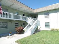 Bright exterior of building with well-maintained landscaping and white staircase and balcony with balustrade at 1250 S Pinellas Ave # 1013, Tarpon Springs, FL 34689