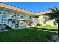 Exterior shot of a two-story light-green building with stairs and a well-maintained lawn at 1250 S Pinellas Ave # 1013, Tarpon Springs, FL 34689