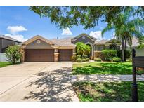 Charming home featuring a well-manicured lawn, a three-car garage, and mature landscaping, showcasing curb appeal at 12801 Stanwyck Cir, Tampa, FL 33626