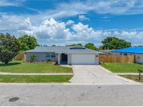 Charming single-story home with a well-manicured lawn, a gray roof, and a two-car garage at 12879 112Th St, Largo, FL 33778