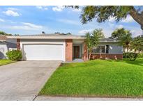 Charming single-story home features a well-manicured lawn and a brick facade at 1667 E Orangeside Rd, Palm Harbor, FL 34683