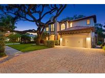 Elegant two-story home with a red tile roof, porte cochere, and meticulously maintained landscaping at 3307 W Knights Ave, Tampa, FL 33611