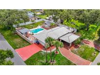 Stunning aerial view of single-story home featuring a large pool, carport, red driveway, and beautifully landscaped yard at 4002 Hudson Ter, Tampa, FL 33618
