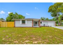 Charming single Gathering home with a well maintained lawn, neutral paint, brick details and attached garage at 4313 Riviera Ct, Spring Hill, FL 34608