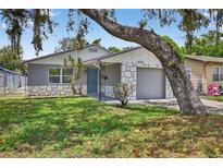 Charming single-story home featuring stone accents, a well-maintained lawn, and mature tree providing shade at 4535 15Th S Ave, St Petersburg, FL 33711