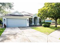 Charming single-story home featuring a two-car garage, well-manicured lawn, and inviting covered entry at 6804 Pleasant Oaks Pl, Riverview, FL 33578