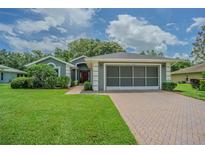 Charming single-story home with well-manicured lawn, brick driveway, and a screened-in two car garage at 10728 Moshie Ln, San Antonio, FL 33576
