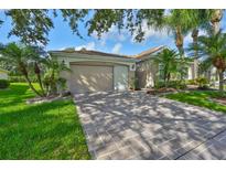 Charming single-story home featuring a two-car garage, paved driveway, and mature landscaping with palm trees at 1112 Mcdaniel St # 78, Sun City Center, FL 33573