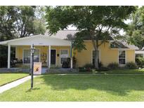 Charming yellow home with a welcoming front porch, mature trees, and a lush green lawn at 13637 13Th St, Dade City, FL 33525