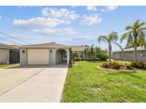 Charming single-story home with a well-manicured lawn and mature palm trees at 13909 Berkowitz Ave, Hudson, FL 34667