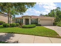 Charming single-story home featuring a lush lawn, manicured landscaping, and a welcoming two-car garage at 19409 Wingrove Ln, Lutz, FL 33558