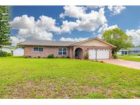Charming single-story brick home featuring a well-manicured lawn and an attached two-car garage at 314 Circle Dr, Palm Harbor, FL 34683