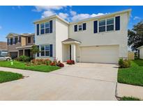 Charming two-story home with blue shutters, white walls, a two-car garage, and well manicured landscaping at 33657 Field Maple Loop, Wesley Chapel, FL 33545