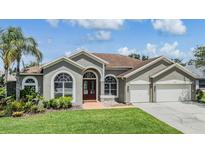 Charming single-story home with a well-manicured lawn, lush landscaping, and a two-car garage at 9126 Cypress Keep Ln, Odessa, FL 33556