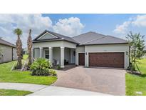 Charming single-story home featuring a brick-paved driveway and a welcoming covered porch with classic columns at 10278 Otter Sky Ct, San Antonio, FL 33576