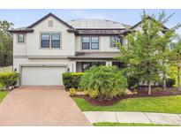Stunning two-story home featuring a brick driveway, lush landscaping, and solar panels on the roof at 10701 Morning Dew Way, Tampa, FL 33647