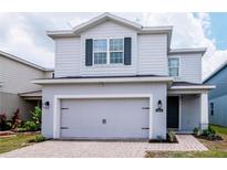 Charming two-story home featuring a gray exterior with a brick driveway and a convenient two-car garage at 12215 Blue Pacific Dr, Riverview, FL 33579
