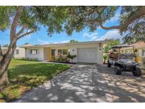 Charming single-story home with a well-maintained lawn, a driveway, and a golf cart at 245 Grove Cir N, Dunedin, FL 34698