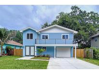 Charming two-story blue home featuring a second story balcony, white trim and an attached garage at 309 Congress St, Oldsmar, FL 34677