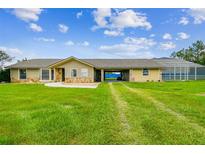 Ranch-style home with a long driveway and a screened pool; large grassy lawn at 34215 Kiefer Rd, Dade City, FL 33525