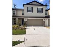 Two-story home featuring an attached garage, stone accents, neutral siding, and manicured landscaping at 36233 Joseph Blake St, Zephyrhills, FL 33541