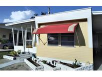Charming home featuring a small porch, awning, and a well-kept garden area with small plants at 4300 E Bay Dr # 309, Clearwater, FL 33764
