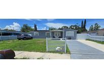 Charming gray home featuring a well-manicured lawn and white picket fence at 5106 Town N Country Blvd, Tampa, FL 33615