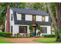 Charming two-story home with a gambrel roof, brick chimney, green door and mature landscaping at 5518 21St S Ave, Gulfport, FL 33707