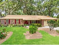 Charming stone home featuring a manicured lawn and vibrant red shutters that add a touch of classic elegance at 616 Pawn Way, Seffner, FL 33584