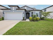 Charming single-story home featuring a well-manicured lawn and a two-car garage in a suburban neighborhood at 9107 Rally Spring Loop, Wesley Chapel, FL 33545